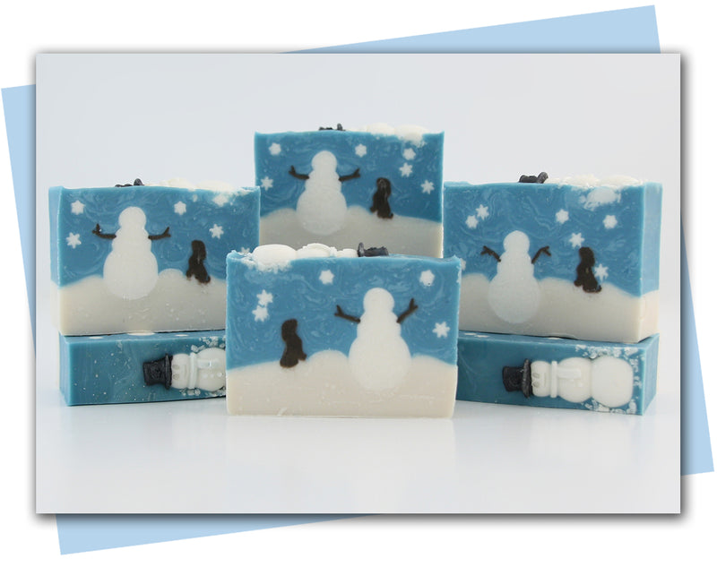 Bars of soap with a snowman design and dog looking at snowman