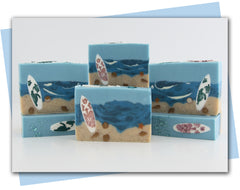 Beach scene with shells and surfboard sittnig in the sand with ocean background bars of soap