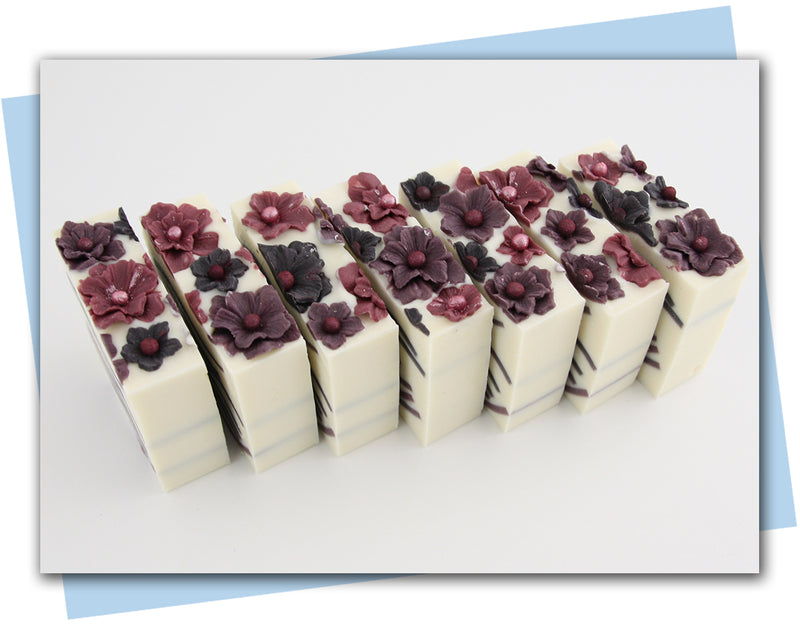 Plum colored flowers on top of soap with plum ombre soap waves throughout the center